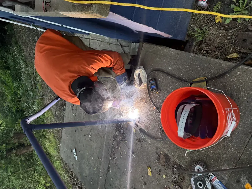 Metal handrail welding repair beside a concrete walkway