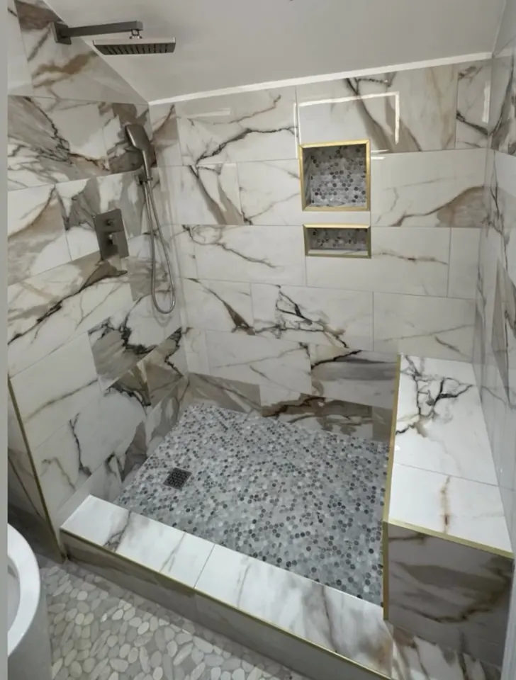 Marble-look tiled shower with mosaic floor and built-in niches