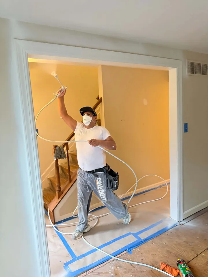 Painter working on interior walls with the floor protected